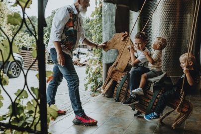 Adults interacting with children enjoying a playful moment indoors on swings.